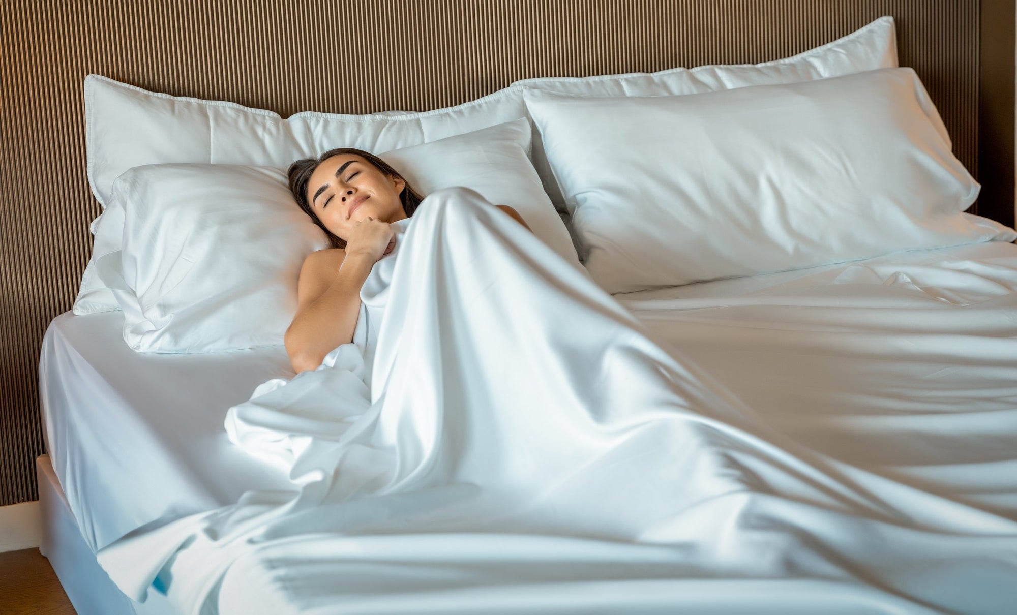 A woman is just waking up and enjoying the comfort of her sustainable eucalyptus sheets.