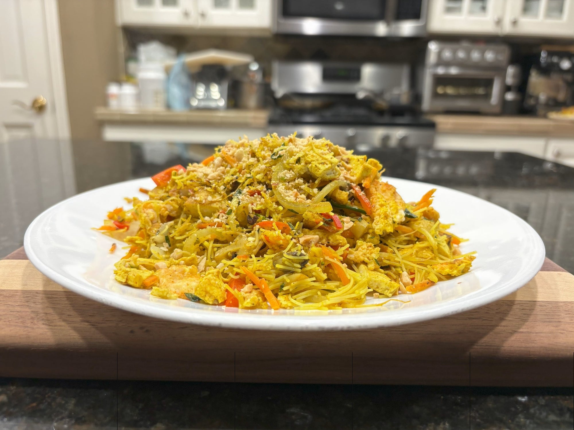 A delicious plate of vegan Singapore noodles sits on a countertop.