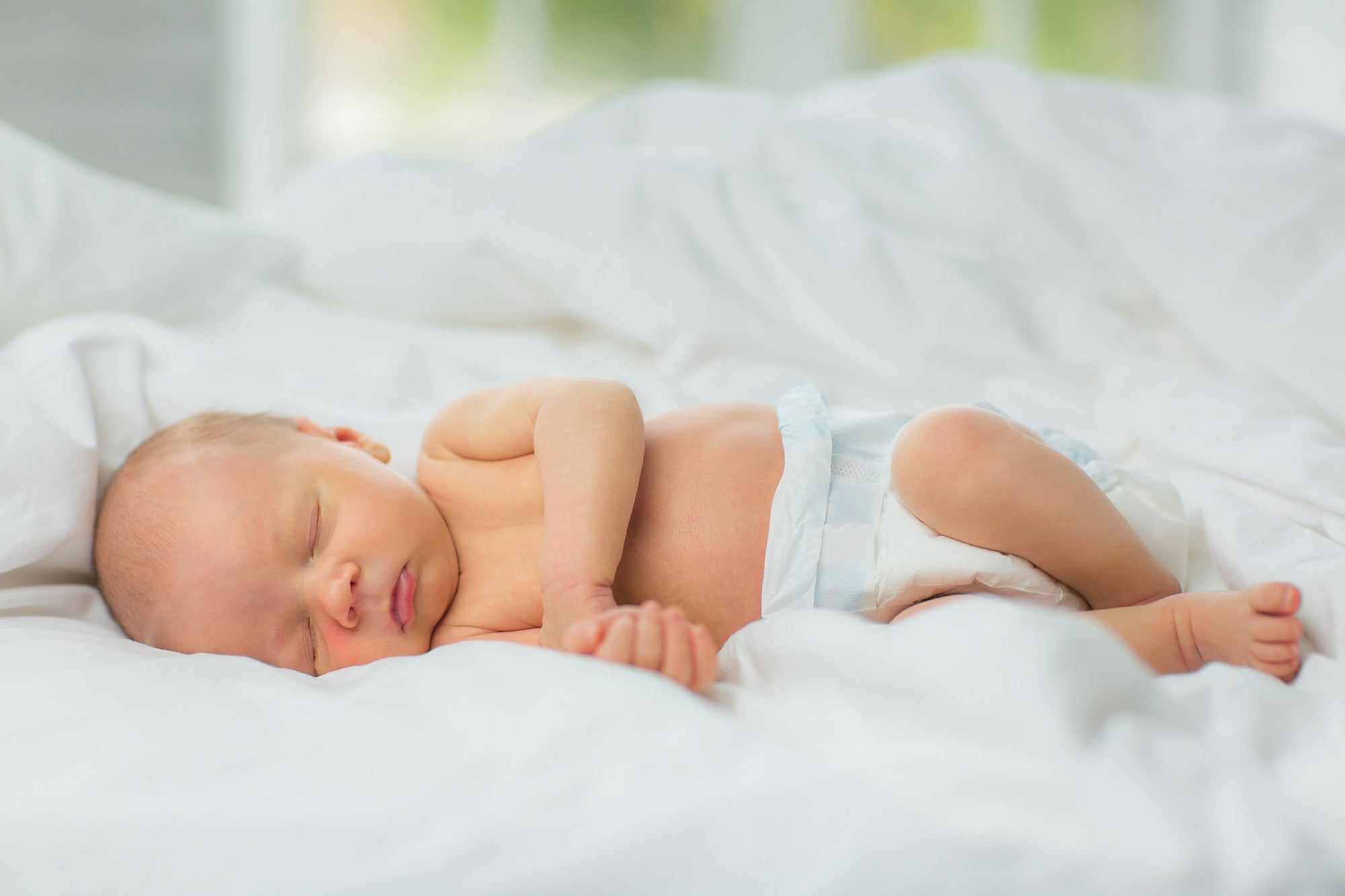 A newborn baby sleeps in undyed, chemical-free, hypoallergenic eucalyptus bedding.