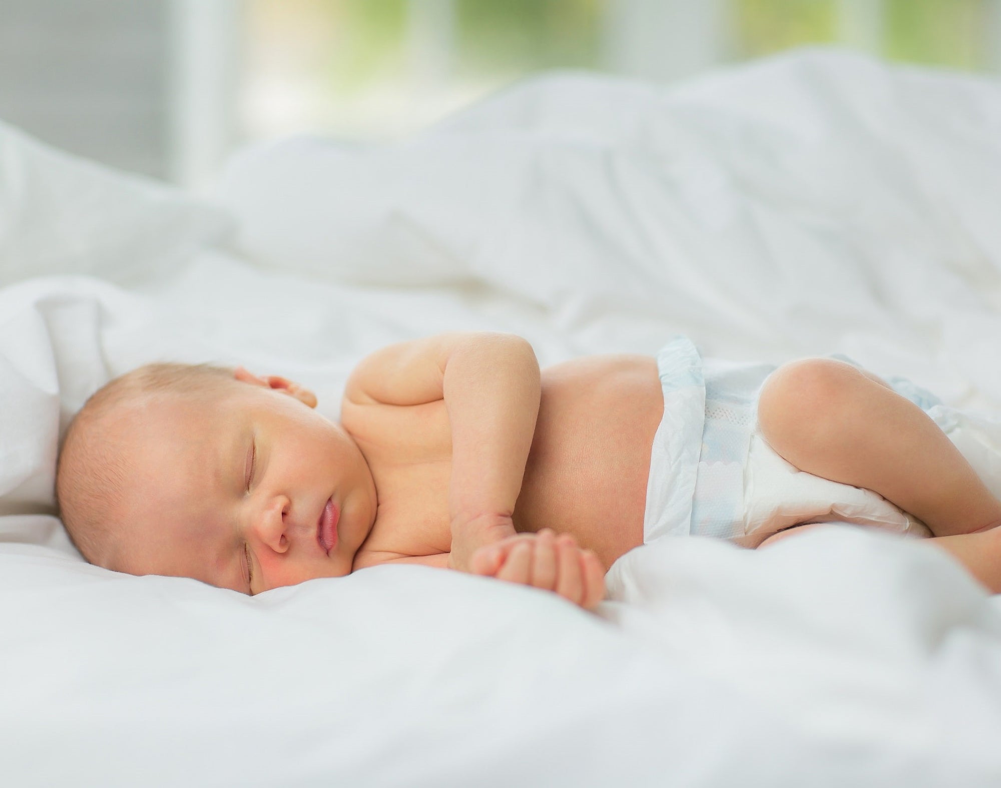 A newborn baby sleeps in undyed, chemical-free, hypoallergenic eucalyptus bedding.