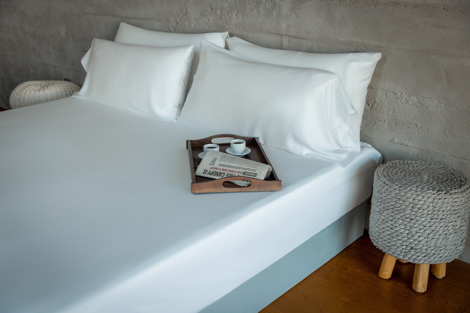 A wooden breakfast in bed tray sits on a bed made with sustainable eucalyptus bedding.