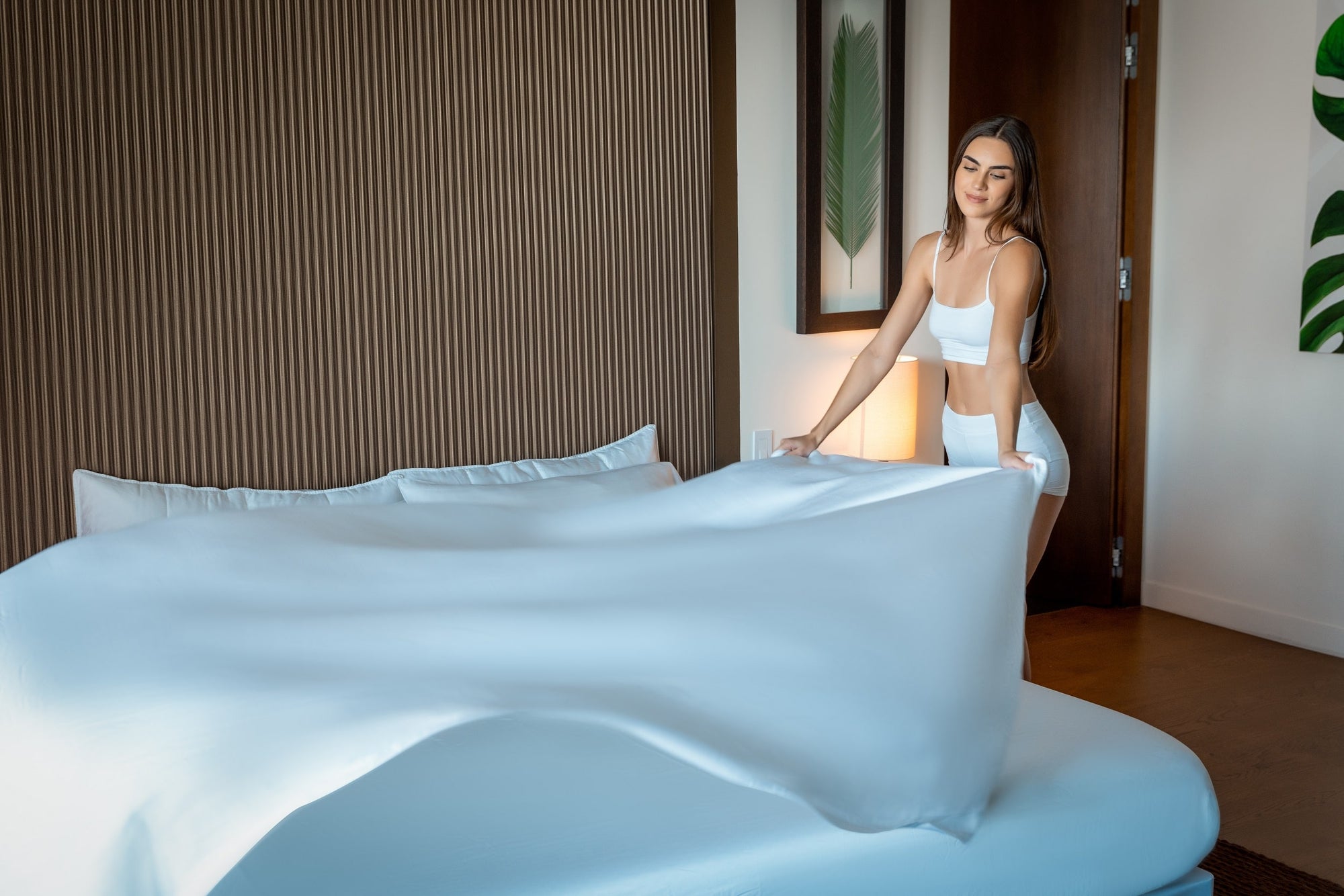 A woman makes her bed with freshly washed TENCEL eucalyptus lyocell bed sheets.