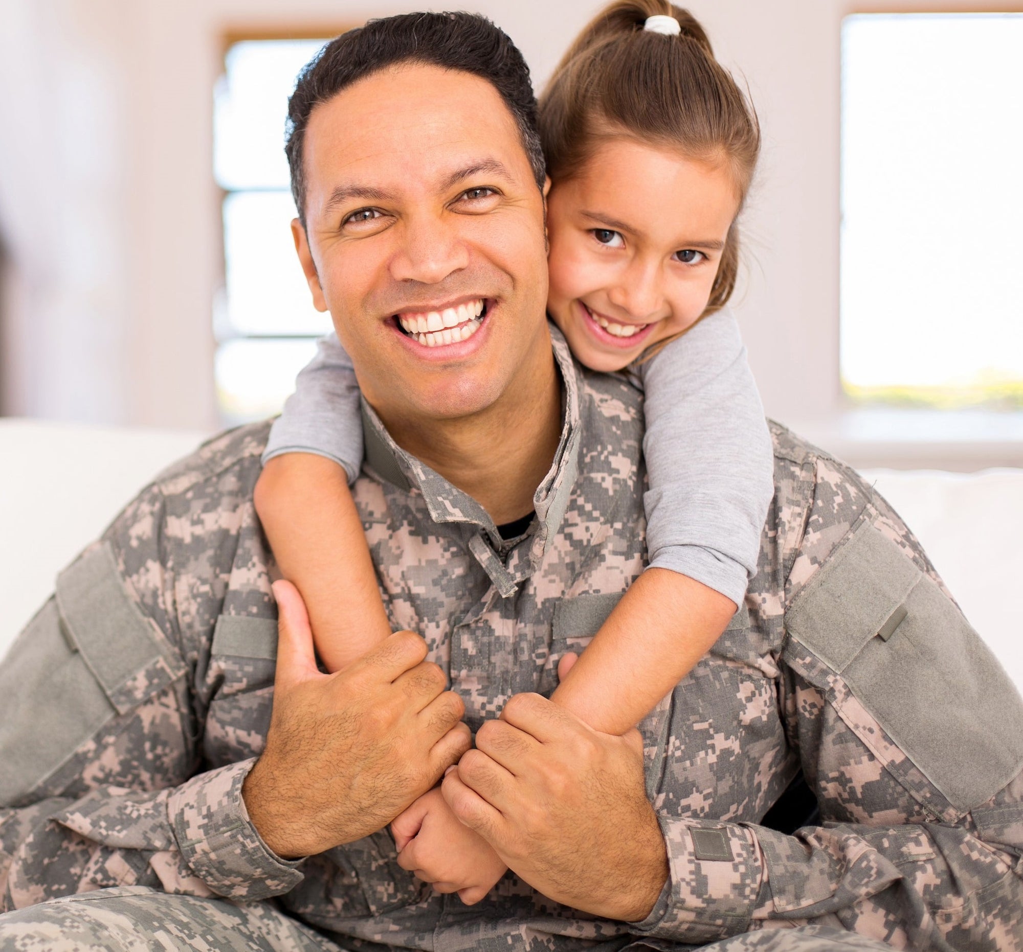 A smiling daughter hugs her military father.