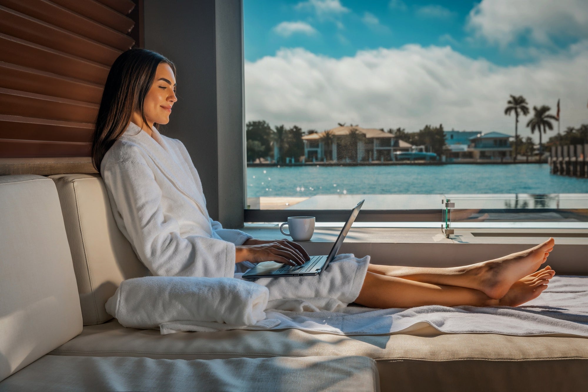 A woman works on her laptop by the pool at a modern, eco-friendly home.