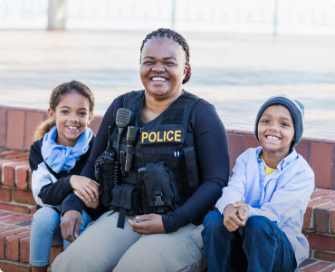 A police officer and her two kids are smiling in appreciation of their police discount.